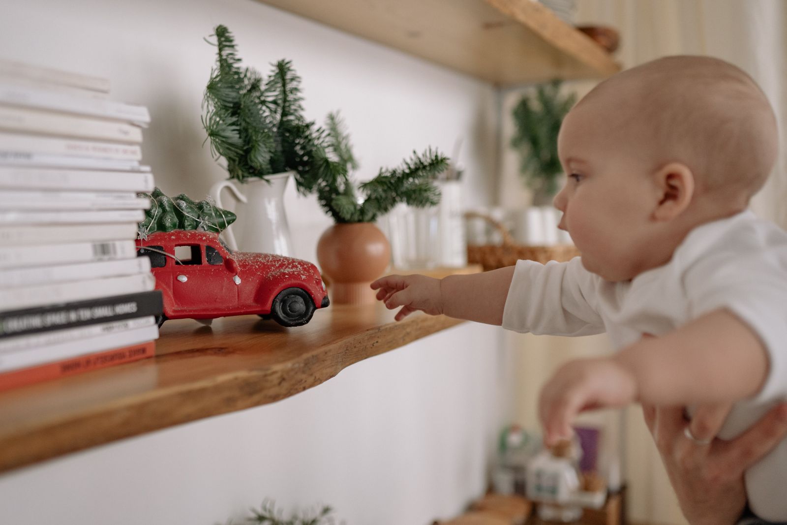 baby reaching for toy on shelf